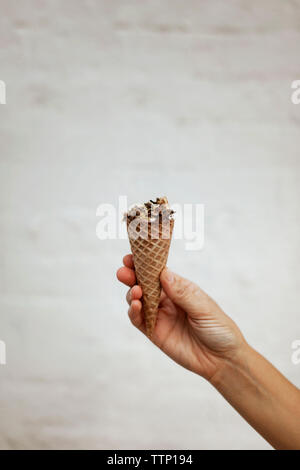 Immagine ritagliata dell'uomo tenendo cono gelato contro la parete Foto Stock