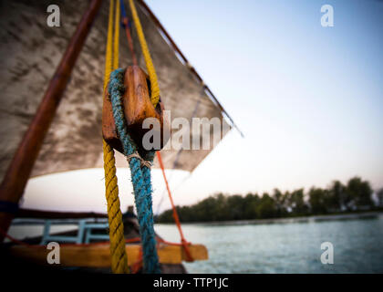 Basso angolo di visione della puleggia in barca a vela in Isola di Mafia contro il cielo blu e chiaro durante il tramonto Foto Stock