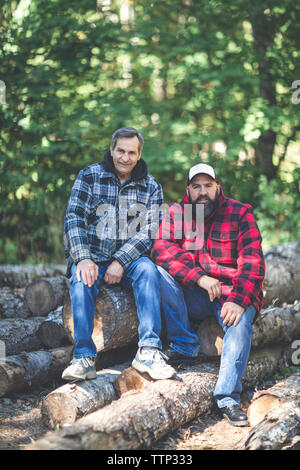 Ritratto di amici seduti su log in foresta Foto Stock