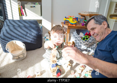 Felice nonno e nipote giocare con blocchi giocattolo nel salotto di casa Foto Stock