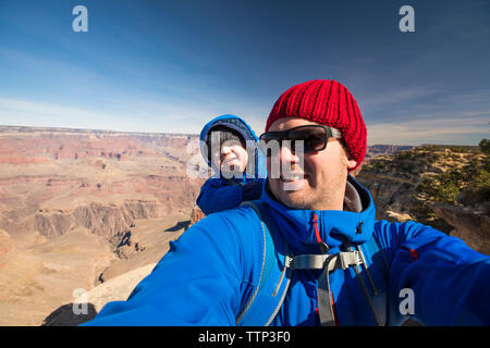 Ritratto di Padre Felice con graziosi figlio permanente al Parco Nazionale del Grand Canyon contro sky durante la giornata di sole Foto Stock