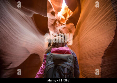 Vista posteriore del padre che porta la figlia mentre si cammina in mezzo a formazioni rocciose a pagina Foto Stock