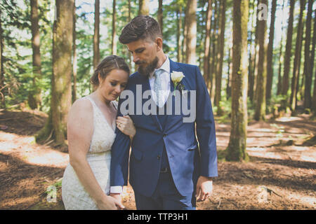 Romantico sposa giovane in piedi contro gli alberi nelle foreste Foto Stock