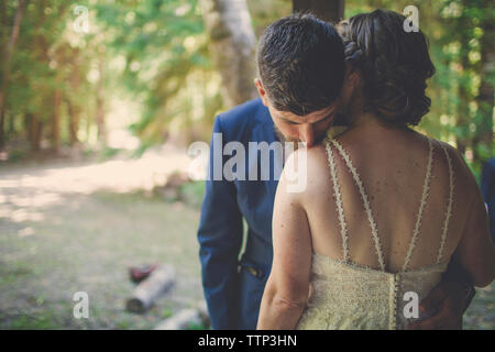 Romantico sposa giovane abbracciando in piedi contro gli alberi nelle foreste Foto Stock