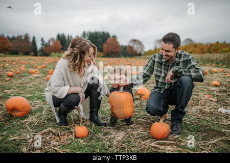 La famiglia felice godendo sulla zucca patch durante l'autunno Foto Stock