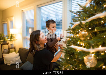 Madre e figlio decorare l'albero di Natale di famiglia Foto Stock