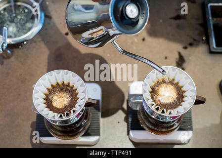 Angolo di alta vista di acqua bollente essere versata in filtri per caffè al caffè Foto Stock