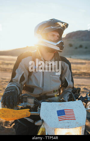 Uomo sulla moto nel deserto durante il tramonto Foto Stock