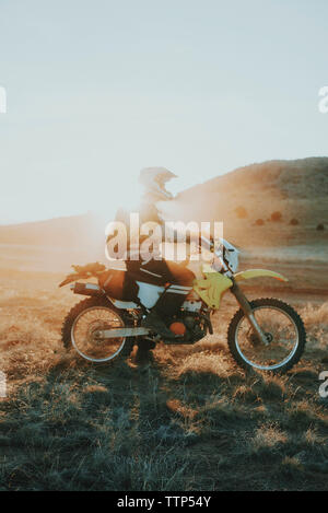 Uomo sulla moto nel deserto durante il tramonto Foto Stock