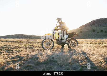 Uomo sulla moto nel deserto durante il tramonto Foto Stock