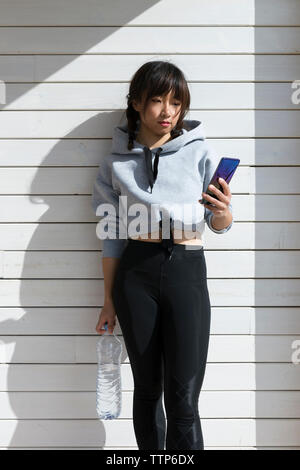 Sportivo da donna asiatica utilizza lo smartphone Foto Stock
