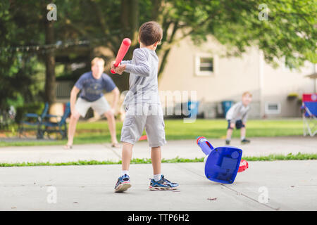 Vista posteriore del ragazzo a giocare a baseball con padre e fratello in posizione di parcheggio Foto Stock