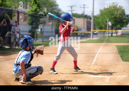 Fratelli a giocare a baseball sul campo durante la giornata di sole Foto Stock