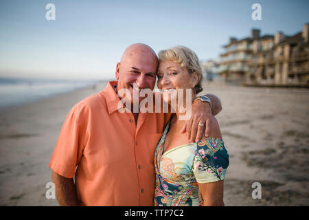 Ritratto di sorridente coppia senior in piedi in spiaggia contro sky Foto Stock