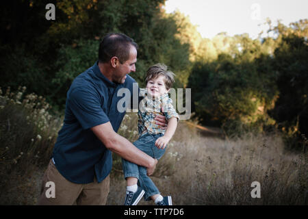 Giocoso padre figlio oscillante durante la riproduzione sul campo Foto Stock