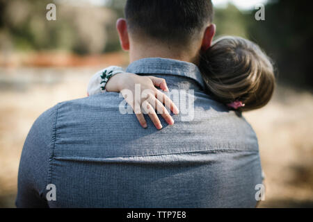 Vista posteriore del padre che porta la figlia sul campo Foto Stock