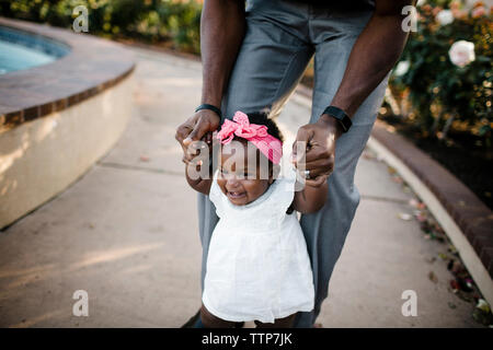 Sezione mediana del padre che assiste la figlia a camminare sul marciapiede in posizione di parcheggio