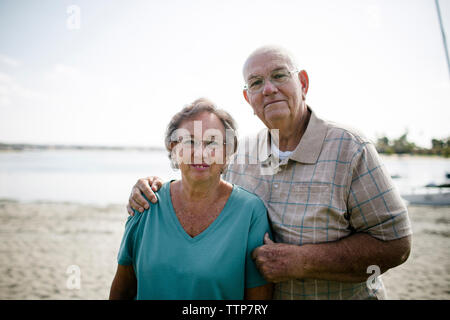 Ritratto di coppia senior in piedi in spiaggia contro sky Foto Stock