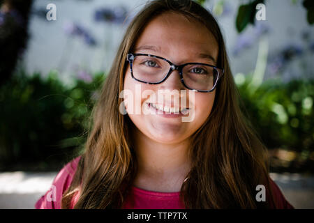 Close-up ritratto della ragazza sorridente indossando occhiali in posizione di parcheggio Foto Stock