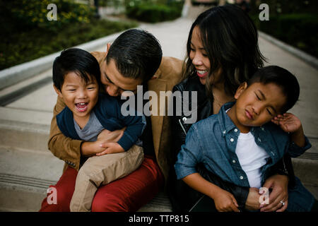 Angolo di alta vista di genitori felici con graziosi figli seduti sui gradini al Balboa Park Foto Stock