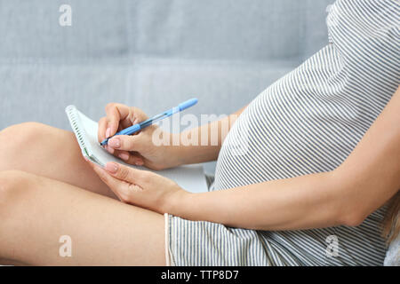 Donna incinta rendendo distinta di imballaggio per ospedale di maternità a casa Foto Stock