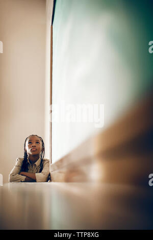 Premurosa ragazza seduta dalla lavagna in aula Foto Stock