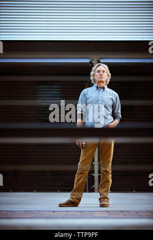 Uomo maturo in piedi sul pavimento con la mano in tasca Foto Stock