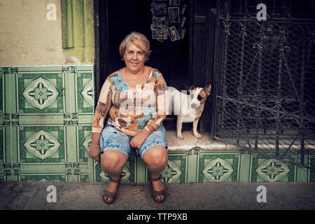 Ritratto di donna seduta dal cane su porta Foto Stock