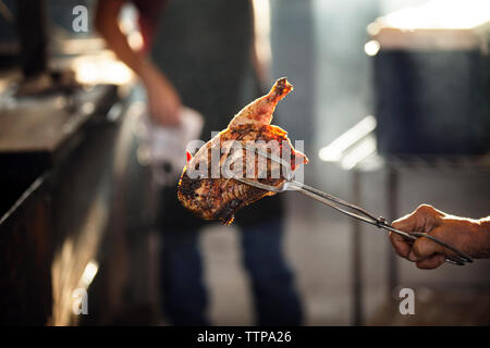 Immagine ritagliata di chef femmina tenendo il pollo mentre un collega in piedi in background Foto Stock