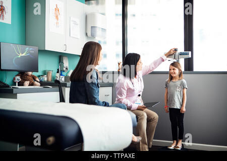 Medico donna ragazza di misurazione dell'altezza in cliniche Foto Stock