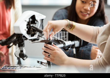 Studentessa elica di fissaggio sul drone con maestro e amico in background Foto Stock