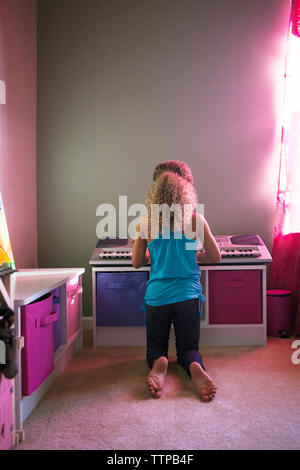 Vista posteriore di una ragazza suonare il pianoforte a casa Foto Stock