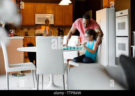 Padre ad assistere la figlia in disegno a casa Foto Stock