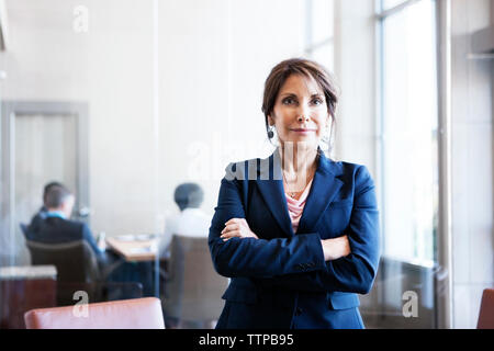 Ritratto di fiducioso imprenditrice con le braccia incrociate in office Foto Stock