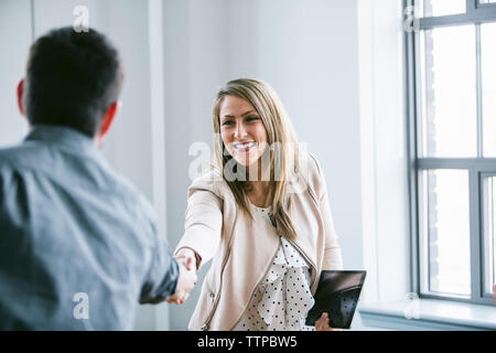 donna d'affari che stringe la mano a un collega maschio in sala riunioni Foto Stock