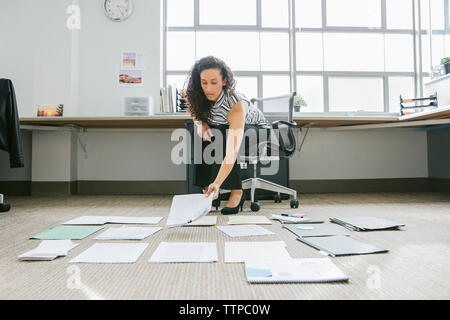 donna d'affari che organizza documenti sul pavimento dell'ufficio Foto Stock