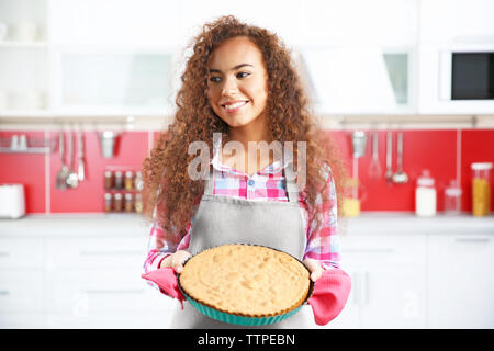 Bella ragazza africana con torta in cucina Foto Stock