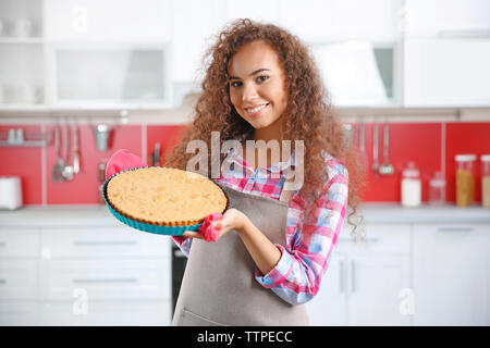 Bella ragazza africana con torta in cucina Foto Stock