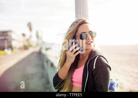 Felice sportive utilizzando smart phone sul marciapiede Foto Stock