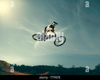 Basso angolo vista del biker eseguendo stunt contro sky Foto Stock