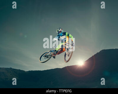 Basso angolo vista del biker eseguendo stunt contro sky durante il tramonto Foto Stock