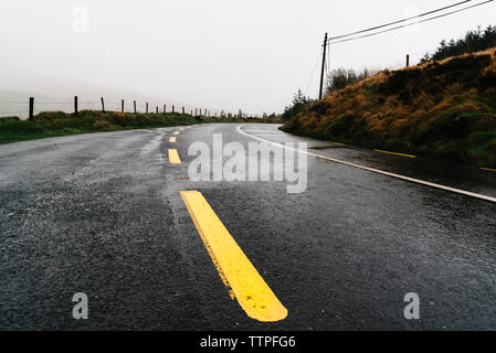 Giallo linee divisorie su strada a vuoto contro sky Foto Stock