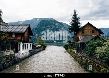 Il lago che scorre tra case contro le montagne del villaggio Foto Stock