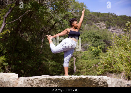 Basso angolo di visione della donna stretching mentre si pratica lo yoga a forest Foto Stock