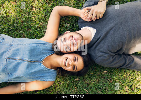 Ritratto di overhead di felice coppia giacendo sull'erba Foto Stock