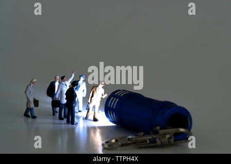 Il gruppo di figurine di business a camminare verso un flusso di luce da una miniatura torcia blu Foto Stock