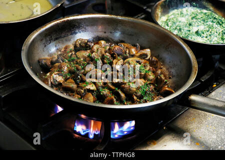 soffriggere i funghi in una padella al fuoco Foto Stock