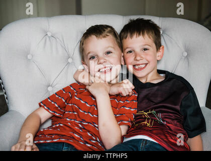 Ritratto di Allegro fratelli seduti su una sedia Foto Stock