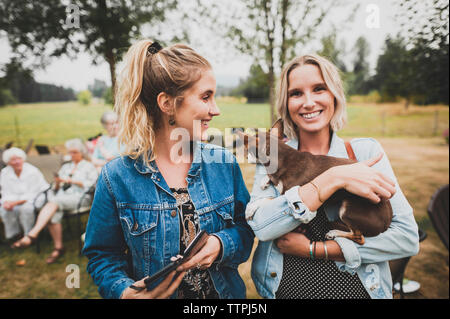 Ritratto di donna holding Chihuahua permanente, mentre con un amico in cantiere Foto Stock