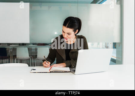 Giovane donna ispanica lavorando sul computer portatile in aula Foto Stock